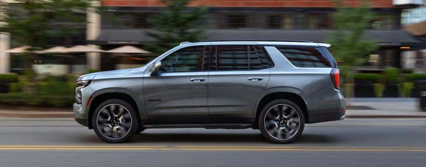 A silver 2025 Chevy Tahoe driving in a city.