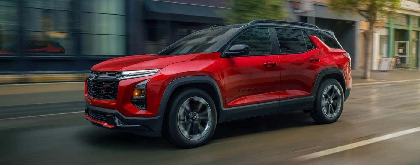 A red 2025 Chevy Equinox RS driving on a city street.