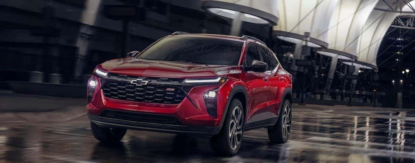 A red 2025 Chevy Trax RS driving on a wet surface.