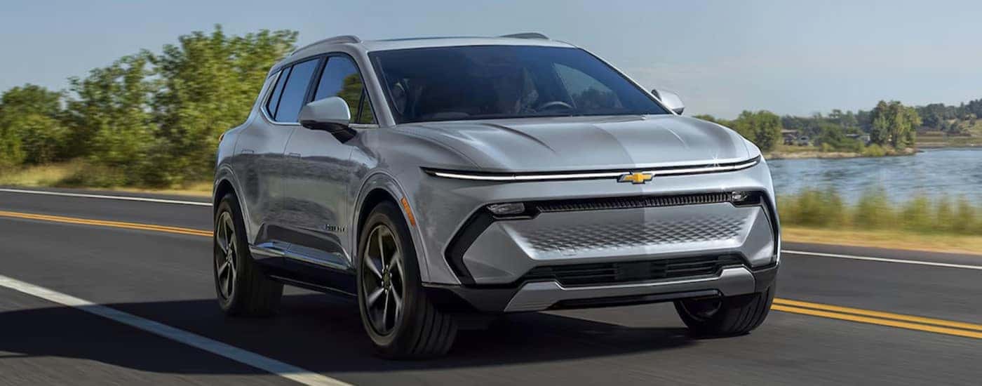 A silver 2025 Chevy Equinox EV driving to view a Chevy Equinox EV for sale near Denver.