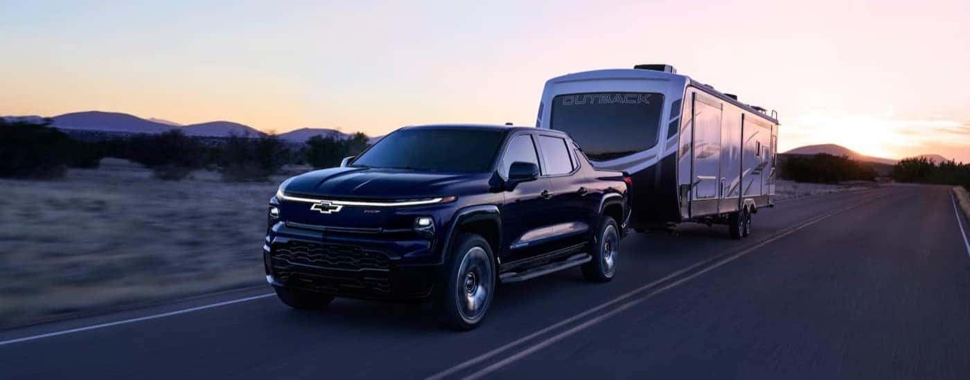 A black 2025 Chevy Silverado EV RST for sale near Statesville is towing a trailer.