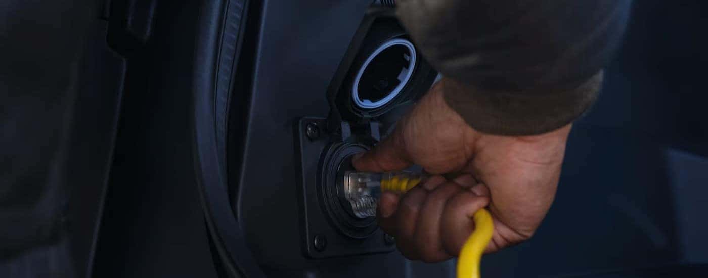 A person utilizing anoutlet on a 2025 Chevy Silverado EV.