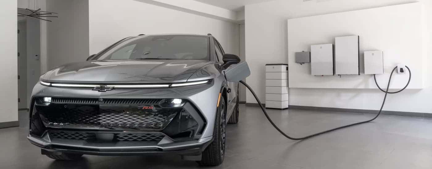 A silver 2025 Chevy Equinox EV charging in a garage