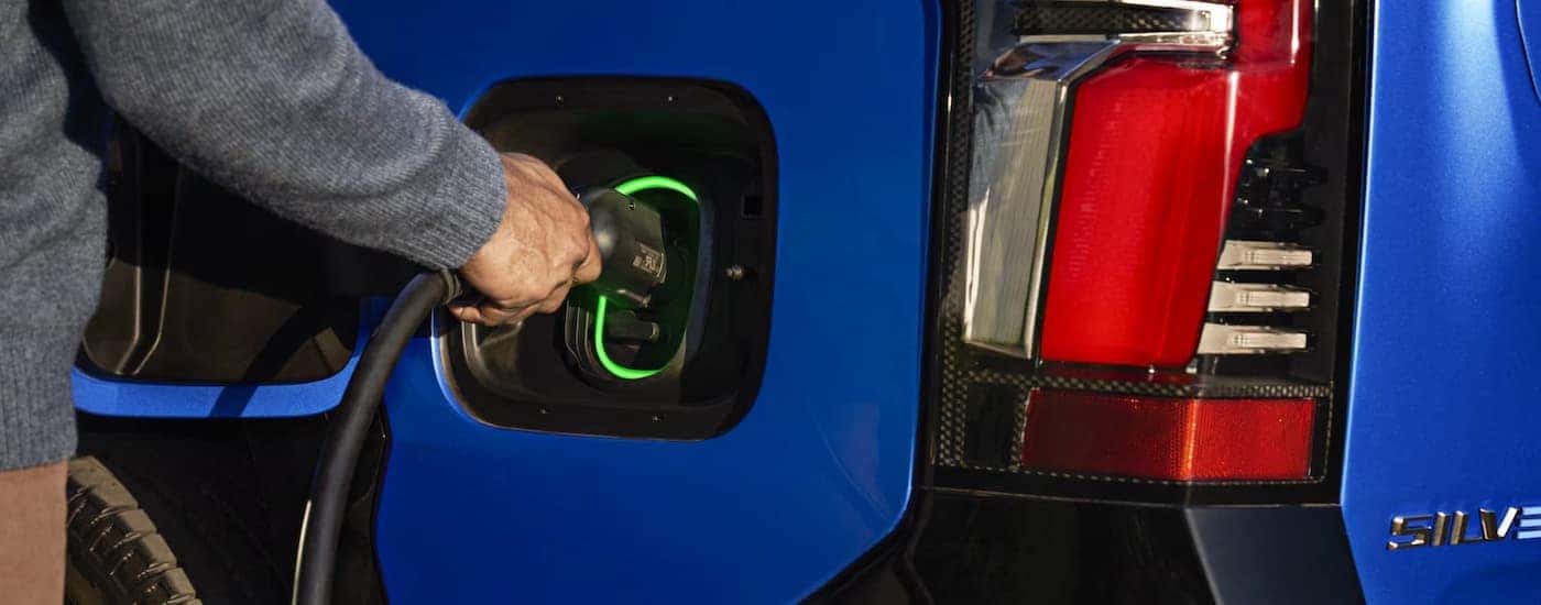 A man plugging in a 2025 Chevy Silverado EV for sale near Denver
