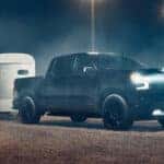 Black 2026 Chevy Silverado 1500 High Country towing a trailer to a Chevy dealer near Denver