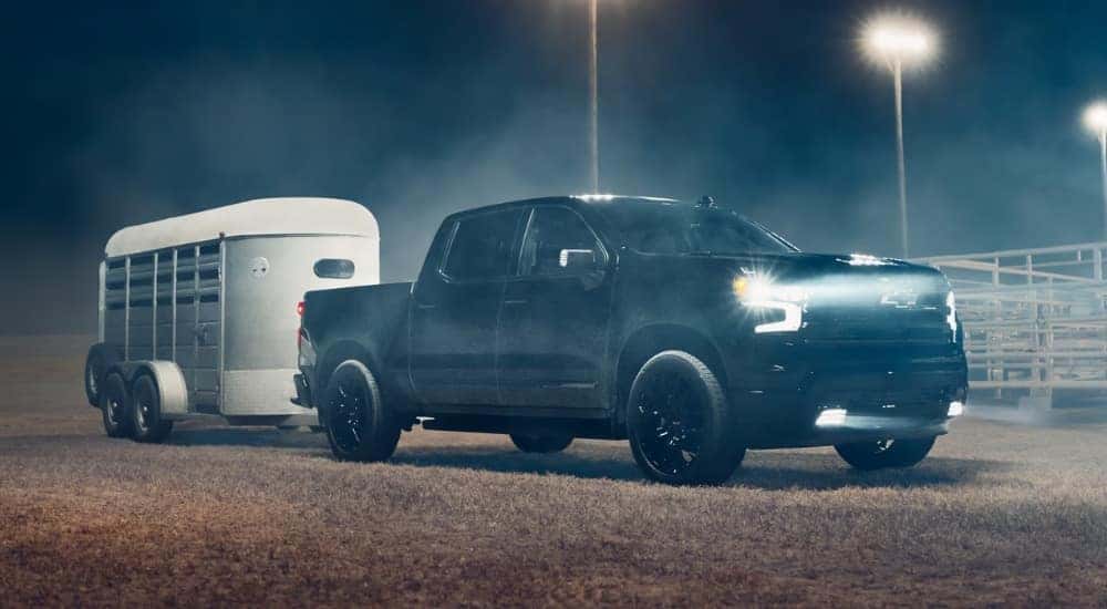 Black 2026 Chevy Silverado 1500 High Country towing a trailer to a Chevy dealer near Denver