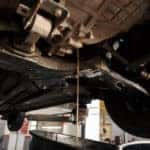 Oil change in automatic transmission. Filling the oil through the hose. Car maintenance station. Red gear oil. The hands of the car mechanic
