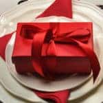 Romantic dinner for two table setting for Valentine's Day with gifts and red accents.