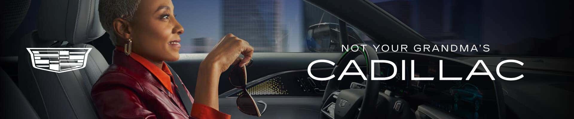 A stylish woman smiles while driving a Cadillac. A caption reads: Not your Grandma's Cadillac.