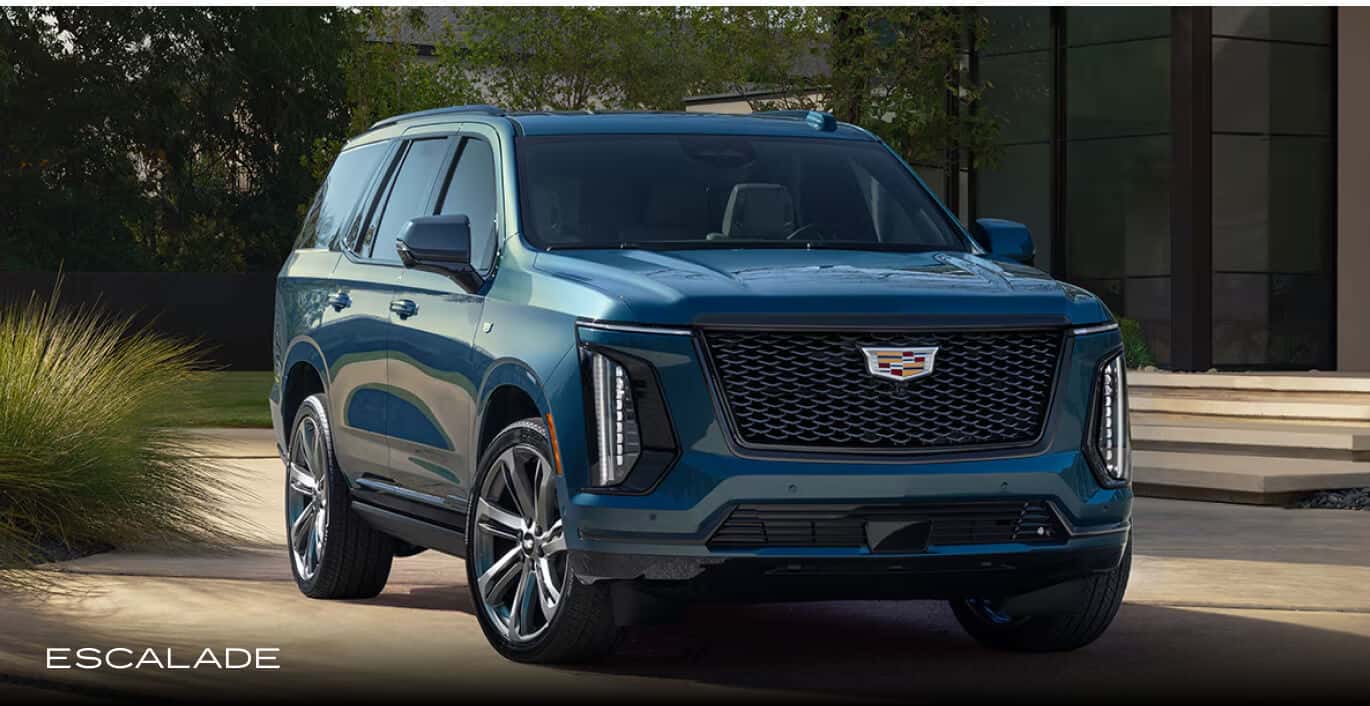 A blue Cadillac Escalade parked in an upscale modern driveway.