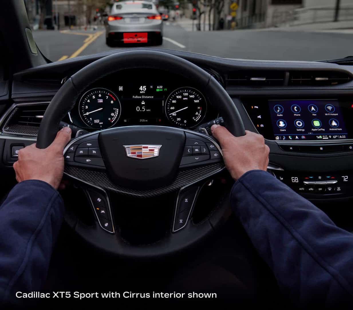 2026 Cadillac XT5 Sport with Cirrus interior, driver’s-eye cockpit view showing steering wheel, gauges and infotainment display.