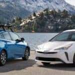 Two 202 Toyota Prius's parked by a lake in the mountains
