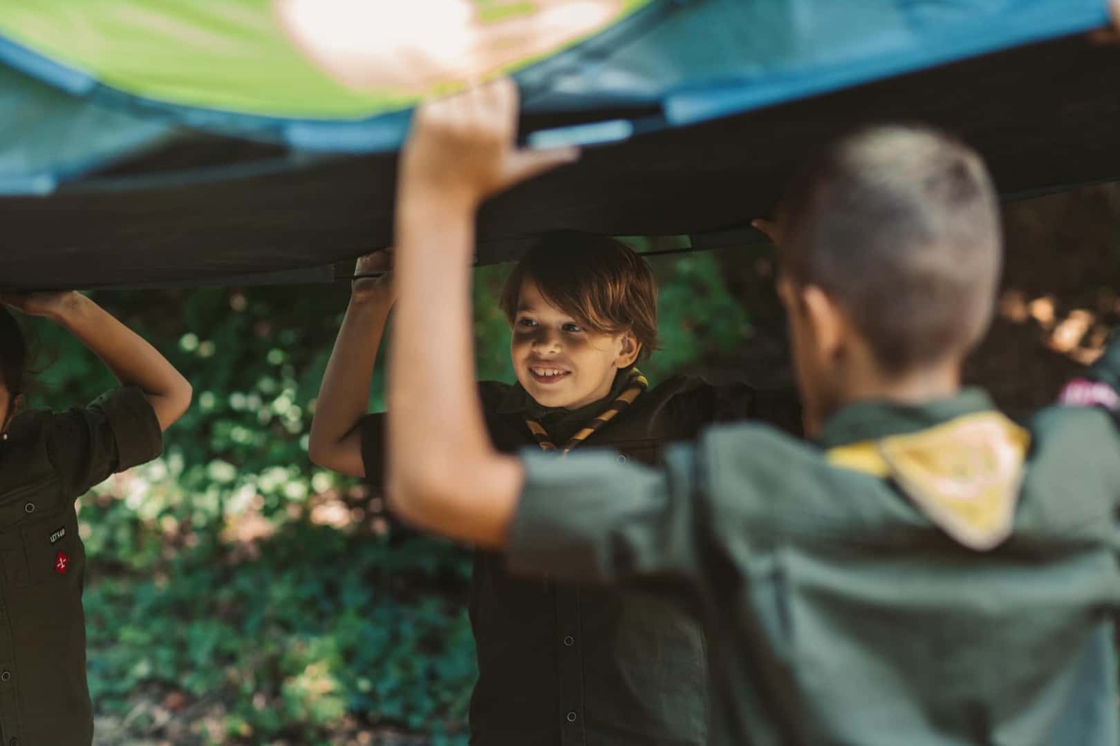 Group of scouts building a tent in forest.