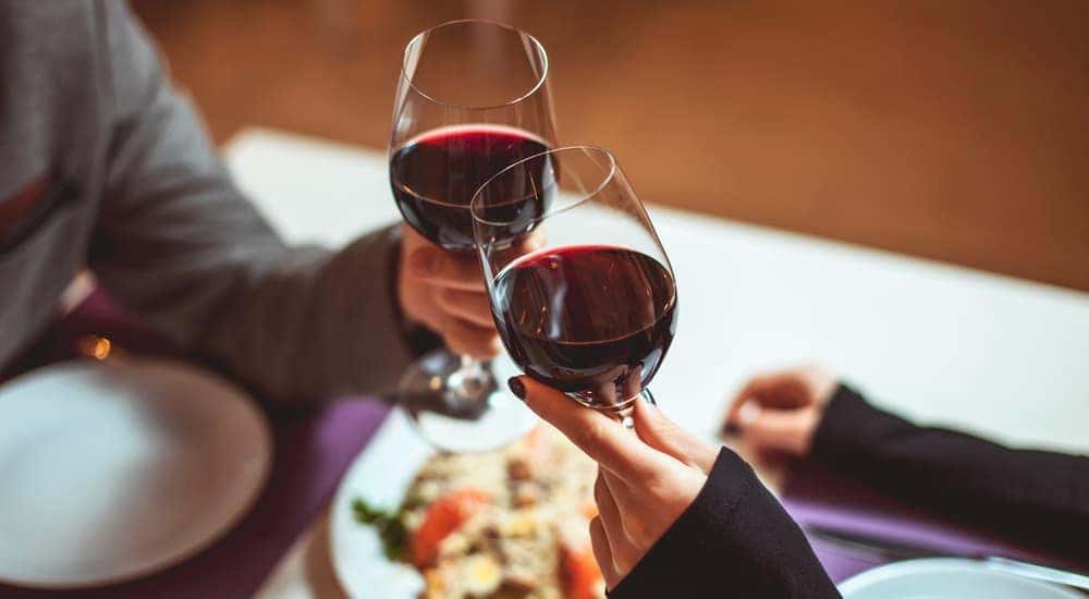 A couple is clinking wine glasses over an Italian meal in Joliet, IL.