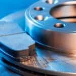 A closeup shows a brake drum and pad sitting on a blue background.