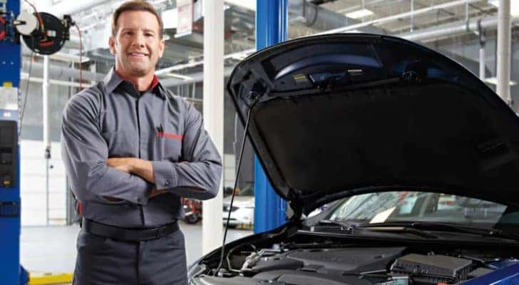 A mechanic at an Illinois Nissan service center is standing next to a blue vehicle.
