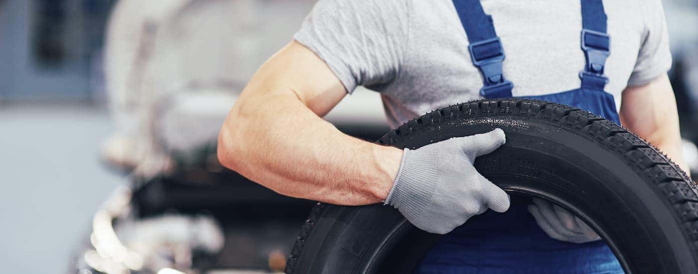 A close up shows a mechanic holding a tire.