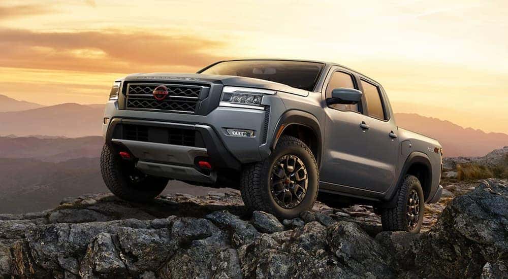 A grey 2022 Nissan Frontier is shown from the side off-roading in the mountains after leaving a Nissan Frontier dealership.
