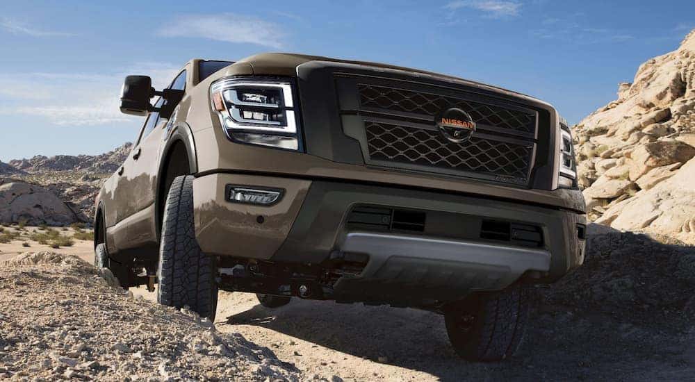 A brown 2021 Nissan Titan PRO-4X is shown from the front off-roading on a rocky trail near a Nissan Titan dealership.