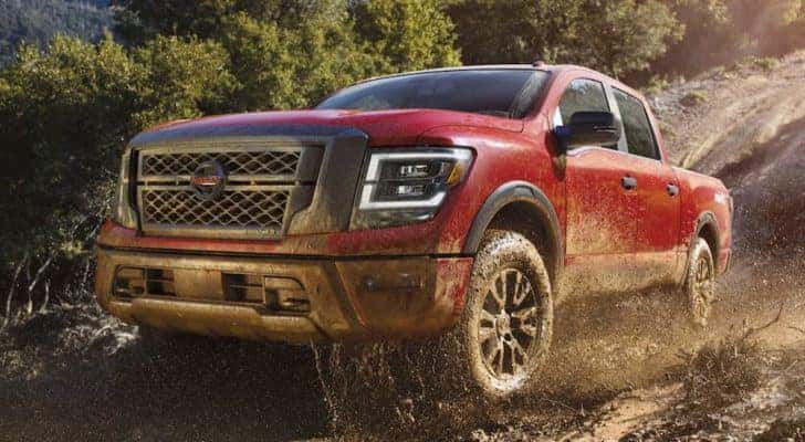 A red 2021 Nissan Titan is shown from the front off-roading through the forest after leaving a Nissan Titan dealership.