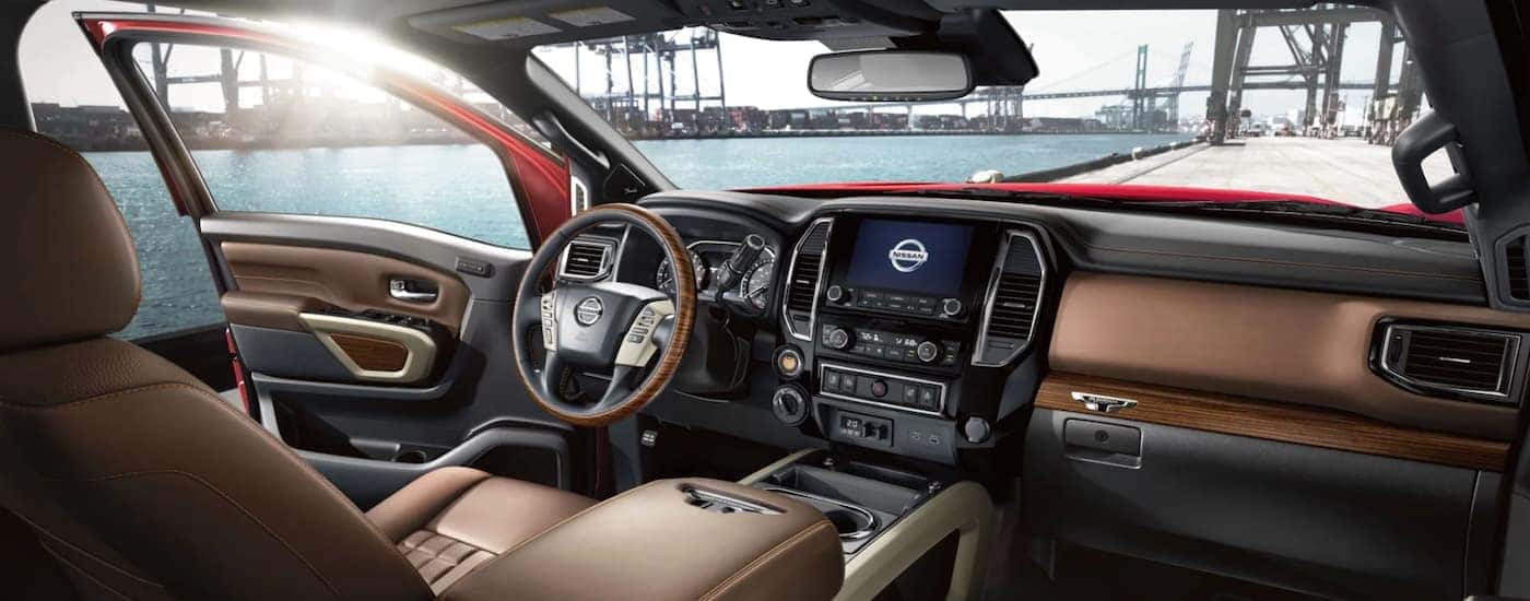 The black and brown interior of a 2021 Nissan Titan shows the steering wheel and infotainment screen.