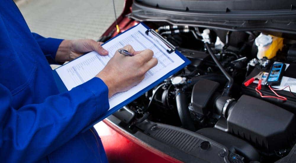 A mechanic is shown performing an inspection for a certified pre-owned Nissan car.