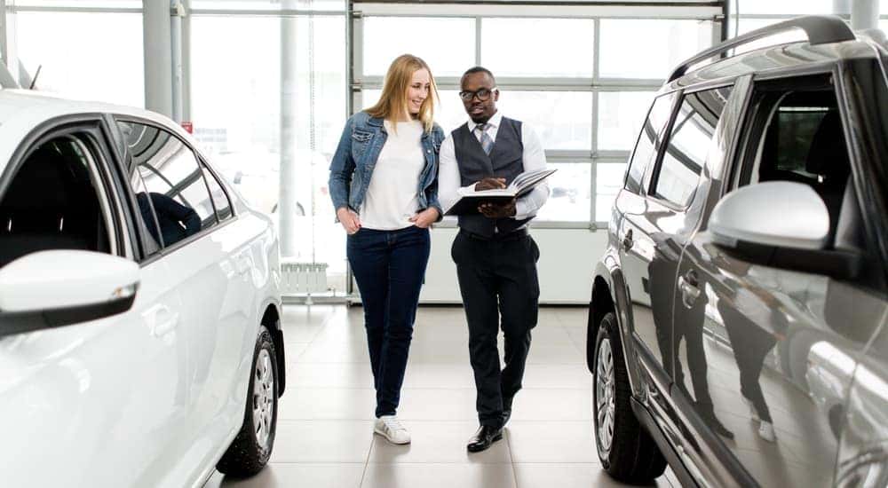 A salesman is shown speaking to a customer about a certified pre-owned Nissan.