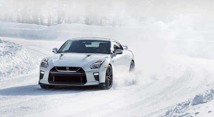 A white 2019 Nissan GT-R is shown rounding a corner in the snow on the way to a winter tire dealer.