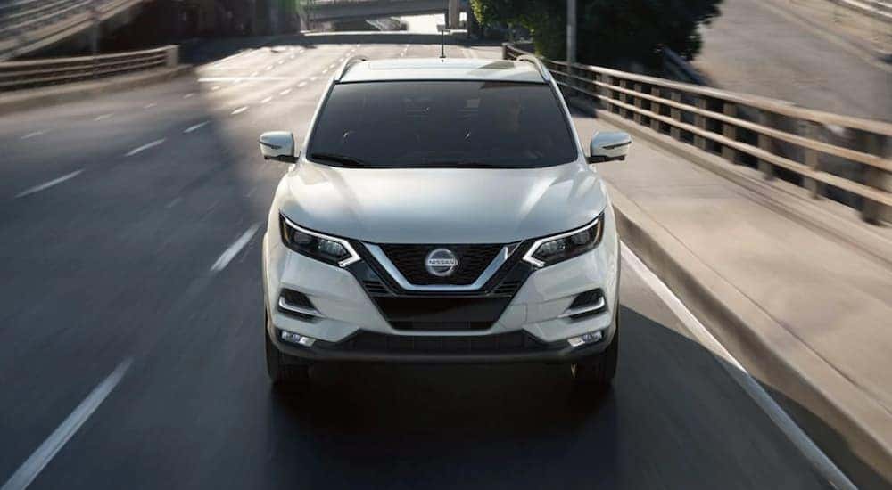 A white 2020 Nisan Rogue Sport is shown from the front driving on a highway.