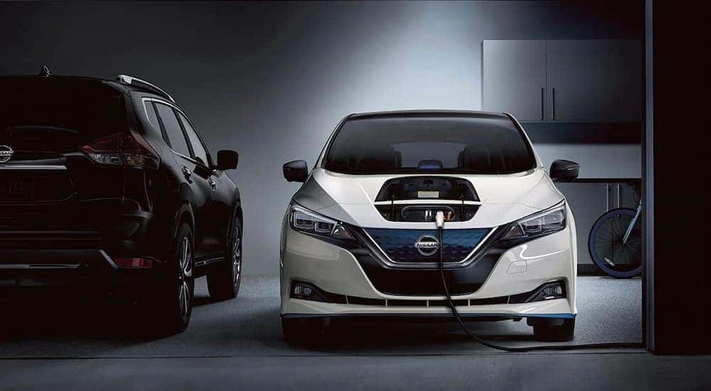 A white 2021 Nissan LEAF is shown charging in a garage after leaving a Chicagoland used Nissan dealer.