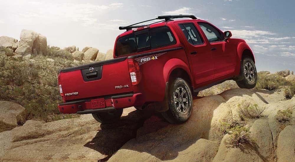 A red 2021 Nissan Frontier PRO-4X is shown from the rear driving on a rocky trail.