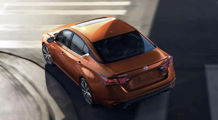 An orange 2022 Nissan Altima is shown rounding a corner from above after leaving a Tinley Park Nissan dealer.