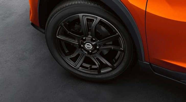 A close up shows the black wheel and tire on an orange 2021 Nissan Kicks.