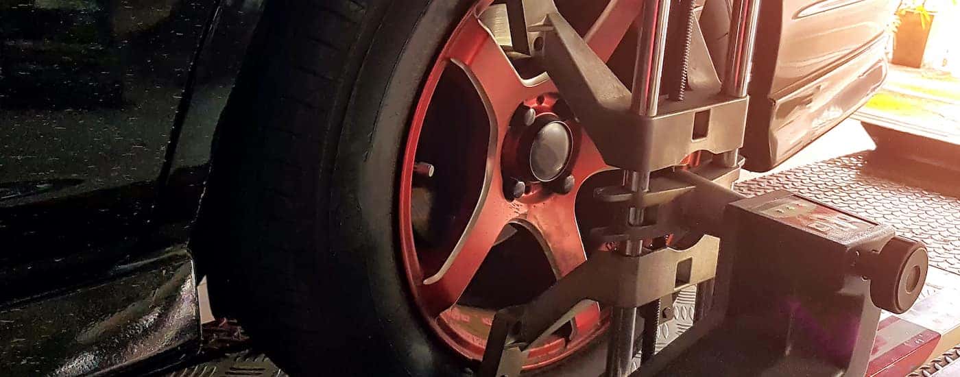A close up shows a wheel being aligned at a dealership.