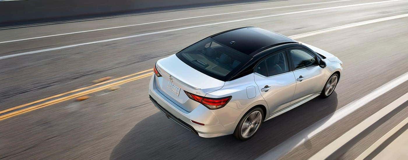 A popular Nissan Sentra for sale near you, a white 2021 Nissan Sentra, is shown from a high angle on a highway.
