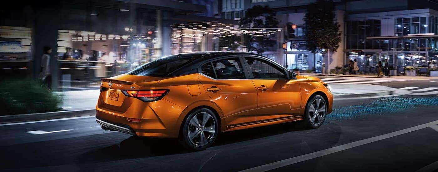 An orange 2022 Nissan Sentra SR is shown from the side on a city street at night.