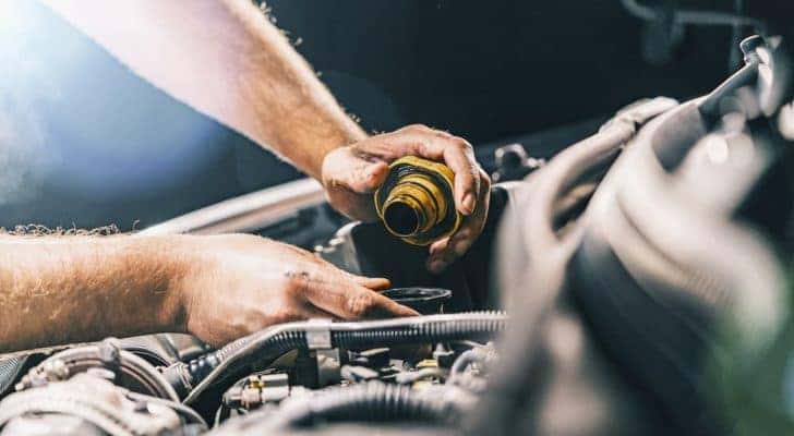 A yellow oil cap is being removed during an oil change near you.