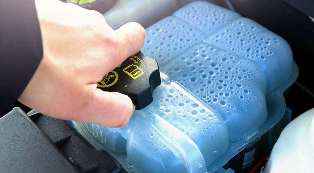 A person is shown checking the coolant during a Crest Hill Nissan service.
