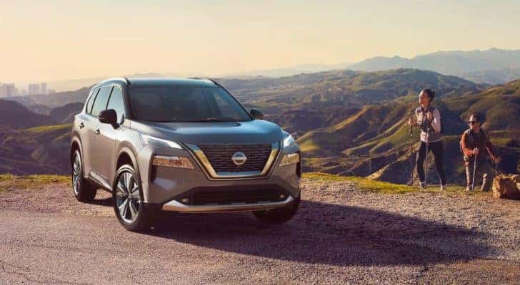 A grey 2022 Nissan Rogue for sale near Crest Hill is shown next to hikers.