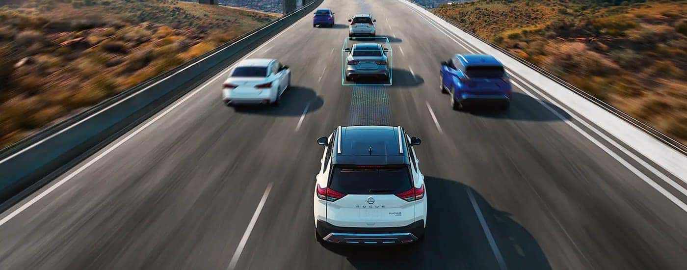 A white 2023 Nissan Rogue is shown with simulated sensor lines on the highway.