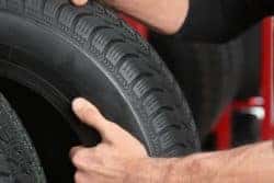 Mechanic hoisting new car tires_mobile
