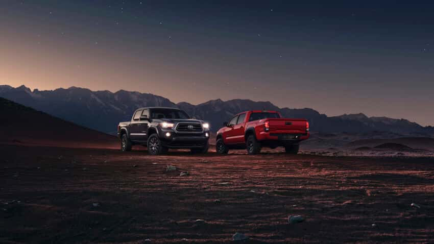 Dos Toyota Tacoma en un dolor desierto con montañas al fondo.