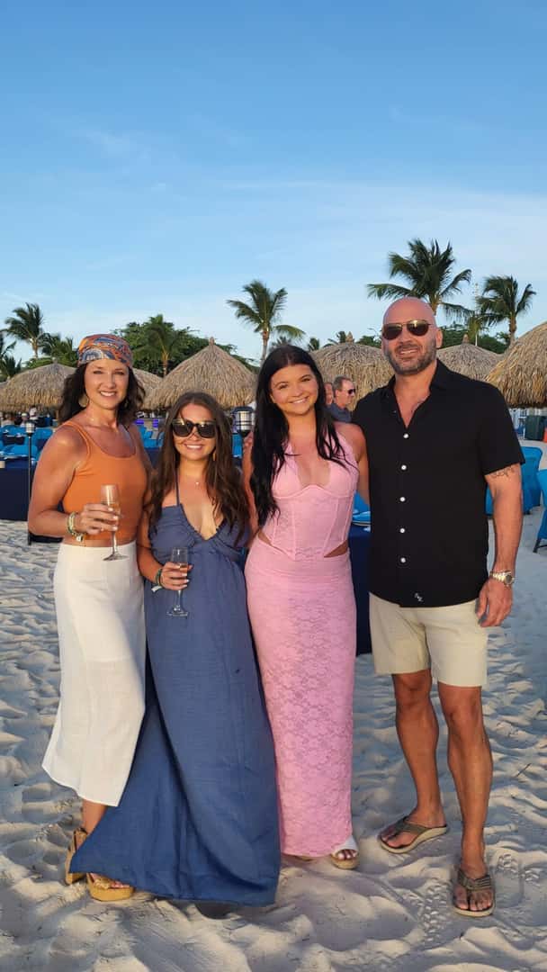 La familia desimone de pie en una playa.