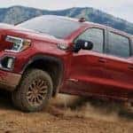 A red 2021 GMC Sierra 1500 AT4 from a GMC dealer near me is off-roading in front of mountains.