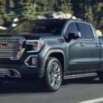 A blue 2021 GMC Sierra 1500 is towing a boat after leaving the GMC truck dealership.