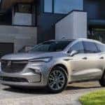 A silver 2021 Buick Enclave Avenir is shown from the front at an angle while parked in front of a house after leaving a Charlotte used car dealer.