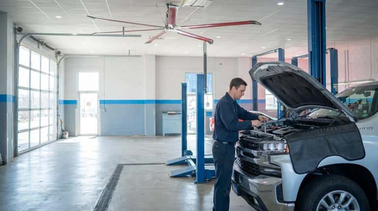 A Yoder Chevrolet technician working on a diesel engine in the Fort Lupton service bay