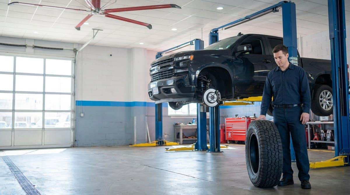 A Yoder Chevrolet technician with a new all-terrain tire in the Fort Lupton service bay