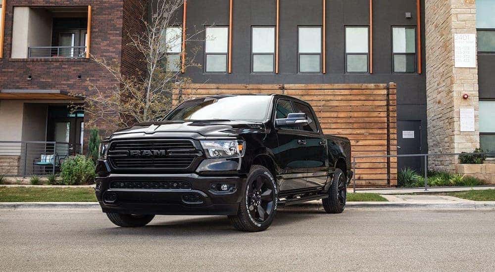 A black 2020 Ram 1500 is parked in front of a modern building with a wooden wall.