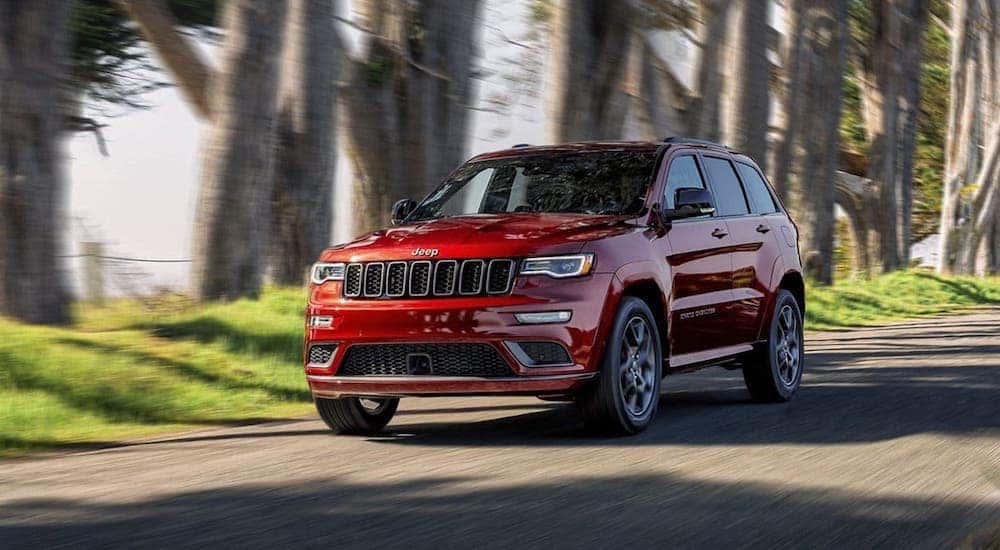 A red 2020 Jeep Grand Cherokee is driving on a tree-lined road near Florence, KY.